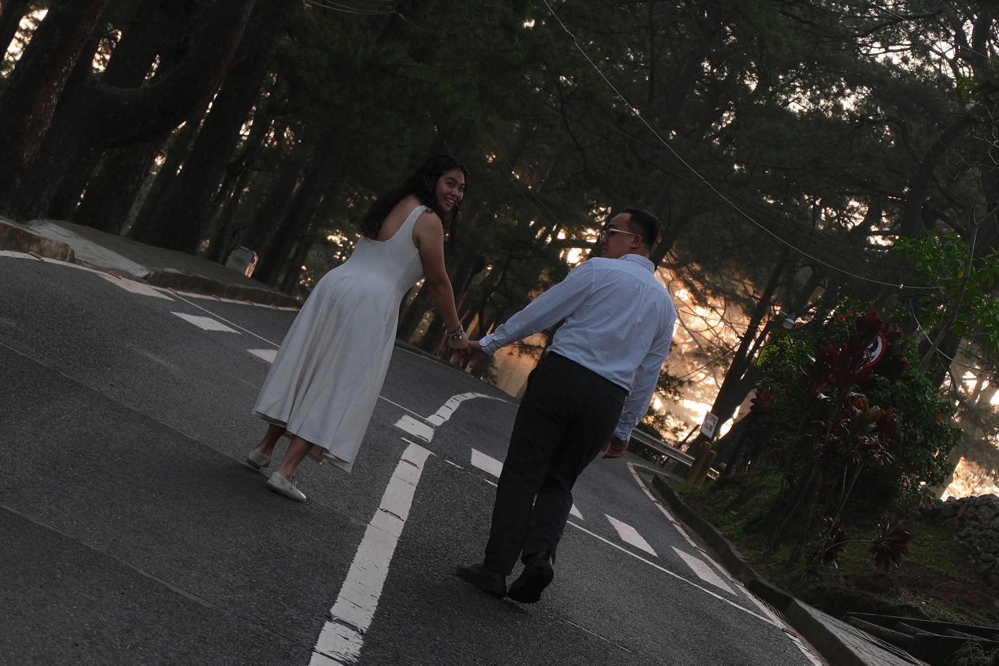 Syd leading Franz up a pine-lined road in Baguio at golden hour
